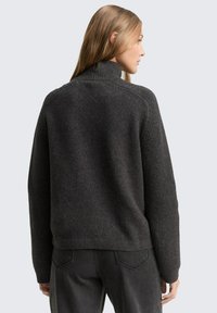 Dunkelgrauer hochgeschnittener Pullover mit gerippten Ärmeln und Rücken, aus strukturiertem Material gefertigt, mit lockerer Passform und dezenten Nähten.