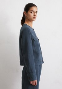 Donkerblauwe linnen jasje met een ronde halslijn, voorknopsluiting, twee borstzakken en lange mouwen, met een ontspannen, verkorte silhouet.