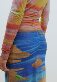 Robe à manches longues avec un design dégradé multicolore comportant des motifs texturés de teintes de coucher de soleil et une scène de l'océan bleu sur la jupe.