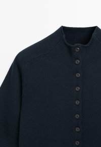 Dunkelmarineblauer Strickcardigan mit hohem Kragen und einer vertikalen Reihe von acht schwarzen Knöpfen vorne.