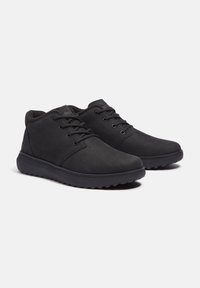 Zapatos de cuero negros con un acabado suave, punta redonda y suela de goma. Presentan un sistema de cordones en la parte delantera y un tobillo acolchado para mayor comodidad.