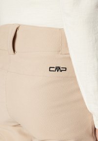 Beige ribbede bukser med en glat talje, der har et sort CMP-logo. Stoffet har en tekstureret finish, der fremhæver dets strukturerede design.