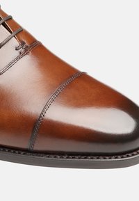 Braune Lederformalschuhe mit einer glatten, polierten Oberfläche. Mit runder Zehenpartie, dekorativen Nähten und Schnürverschluss.
