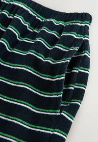 Shorts en tissu éponge bleu marine avec taille élastique, présentant des rayures horizontales blanches et vertes ainsi qu'une poche latérale.