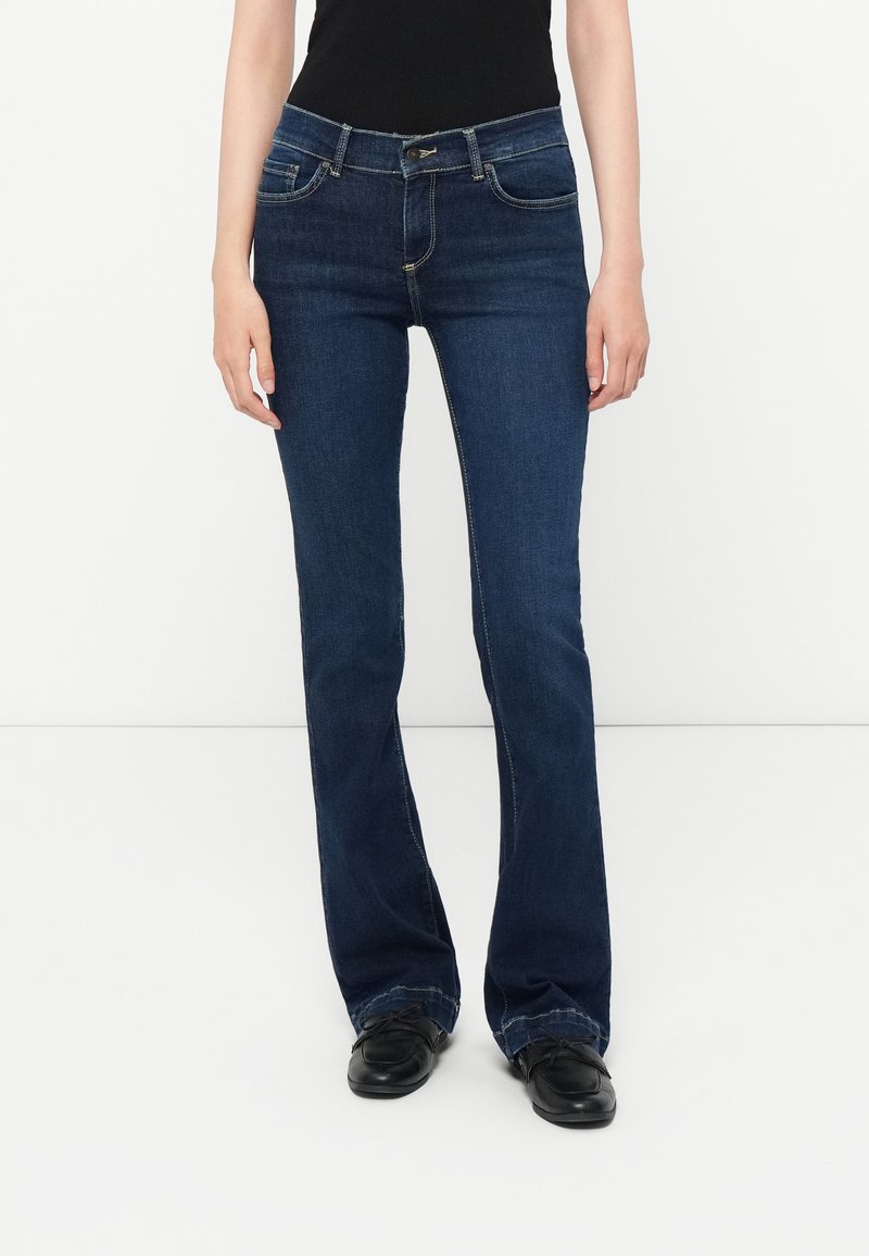 Dark blue flared jeans made from denim, featuring a button and zipper closure, five pockets, and stitched detailing along the seams.