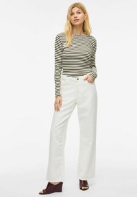Langsleeve gestreepte top in zwart en wit, gecombineerd met losse hoge taille witte broek. Kenmerkt een ronde halslijn en een lichte ribbelstructuur.