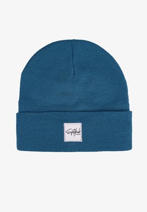 Knitted beanie hat in teal blue with a ribbed texture. Features a folded cuff and a square logo patch on the front.