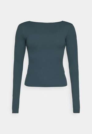 Langsleeve top in donker teal, met een ronde halslijn, slim fit en zachte, rekbare stof. Geen patronen of versieringen zichtbaar.