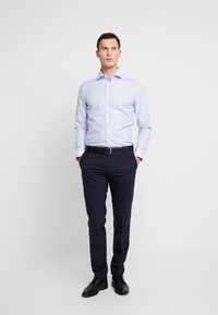 Helles blau gestreiftes Langarmhemd, marineblaue Hose, schwarzer Gürtel und schwarze Schuhe. Schmale Passform mit klassischem Kragen und Knopfverschluss.