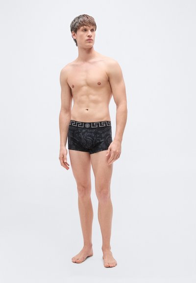 Μαύρα ανδρικά μποξεράκια με τύπωμα και ζώνη μέσης με σχέδιο. Το ύφασμα είναι λείο και το σχέδιο διαθέτει διακριτική υφή και κομψή εφαρμογή.