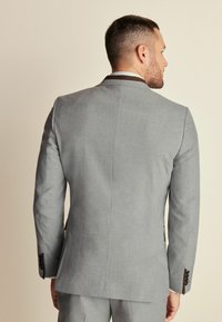 Chaqueta de traje gris con un acabado texturizado, de corte Slim Fit y con solapas de muesca. Presenta botones negros y una sutil abertura trasera para un aspecto a medida.