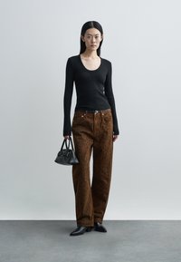 Melna ribota garroku topa ar vaļīgām brūna leoparda printa džinsu biksēm un mazu melnu somiņu, papildināta ar smailām melnām kurpēm.