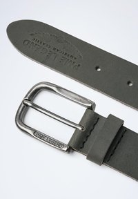 Ceinture en cuir vert avec une boucle en métal, présentant un marquage en relief et des surpiqûres contrastées le long du bord.
