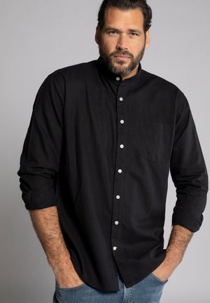 Zwarte lange mouw button-up shirt met een kraag, zak op de linkerborst en opgerolde mouwen, gedragen met blauwe jeans.