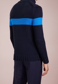 Maglione lavorato a maglia blu navy con una ampia striscia orizzontale blu brillante, caratterizzato da un collo alto e un orlo a coste. Tessuto strutturato con maniche lunghe.