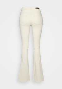 Valkoiset leveälahkeiset farkut, joissa on korkea vyötärö, kaksi takataskua ja sileä, hieman teksturoitu kangas. Lahkeensuut ovat hieman leveät, mikä luo leveälahkeisuuden vaikutelman.