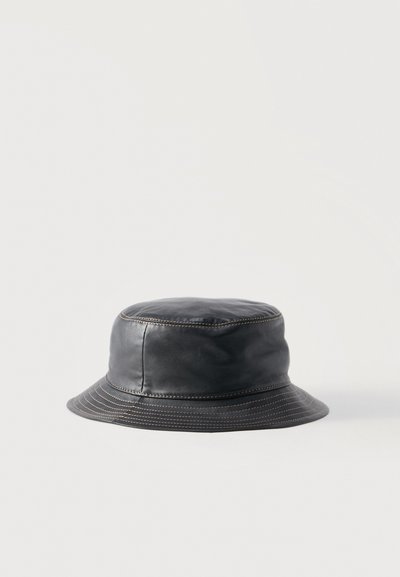 Cappello a secchiello in pelle nera con cuciture marroni visibili attorno alla corona e alla tesa, mostrato su sfondo bianco.