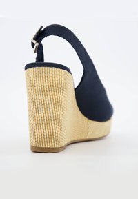 Sandalo con zeppa blu navy con una piattaforma in paglia testurizzata e fascia posteriore. Sopra in tessuto liscio, fibbia regolabile e base beige solida.