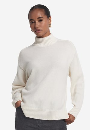 Kremowy sweter z dzianiny z wysokim prążkowanym kołnierzem, luźnym krojem i prążkowanymi wykończeniami. Miękka tekstura, długie rękawy oraz minimalistyczne detale.