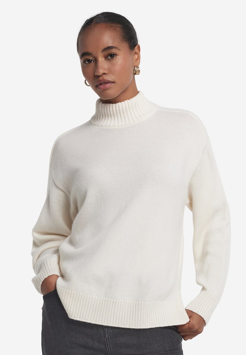 Cremefarbener Strickpullover mit hohem Rippenkragen, weiter Passform und gerippten Säumen. Weiche Textur, lange Ärmel und minimalistische Designdetails.