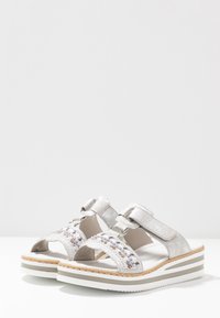 Sandali argentati con decorazioni floreali multicolori, due cinturini regolabili, suole piatte e un sottopiede texturizzato.