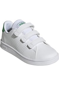 Zapato deportivo blanco con un exterior de cuero suave, tres correas de velcro ajustables, un acento verde en el talón y detalles perforados.