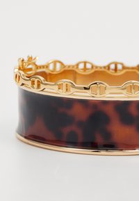 Tortoiseshell bangle with gold-tone metal accents, featuring a linked chain design on the upper edge and a smooth glossy surface.