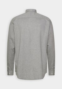 Chemise gris clair à manches longues avec un col boutonné, fabriquée en tissu texturé. Elle possède un ourlet droit et des poignets à boutons, sans motifs visibles.