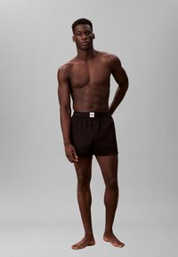 Czarne kąpielówki wykonane z gładkiego materiału, z elastycznym pasem w talii i małą metką z logo Calvin Klein z przodu.