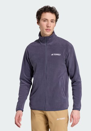 Veste en polaire de couleur violet foncé, dotée d'un col haut, d'une fermeture éclair sur toute la longueur à l'avant et d'un logo blanc "TERREX" sur la poitrine gauche. Texture douce.