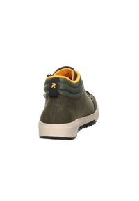 Sneaker vert, mi-haut, avec une texture matelassée, semelle beige et doublure intérieure jaune vif. Présente une étiquette de logo à l'arrière.