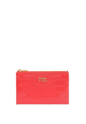 Billetera de piel sintética de color rosa fuerte con textura de cocodrilo, que presenta un cierre dorado y un logo grabado en la parte frontal. Forma rectangular compacta.