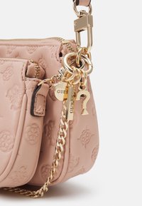 Różowa skórzana torebka z wytłoczonym wzorem, złotymi detalami, łańcuszkowym akcentem i zapięciem na zamek. Zawiera dekoracyjne charmsy.
