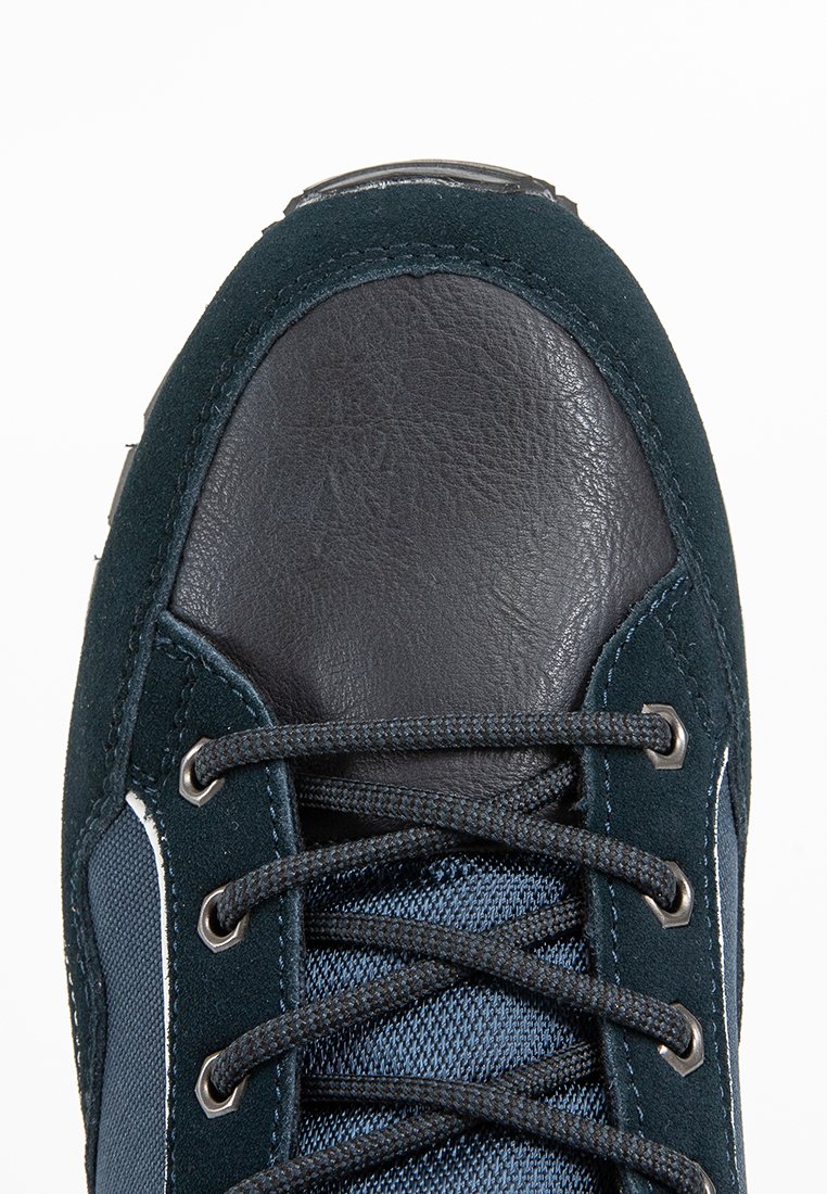Zapatilla de deporte de color azul oscuro que presenta una combinación de ante y tejido texturizado, con una puntera de cuero negro y ojales de metal para los cordones.