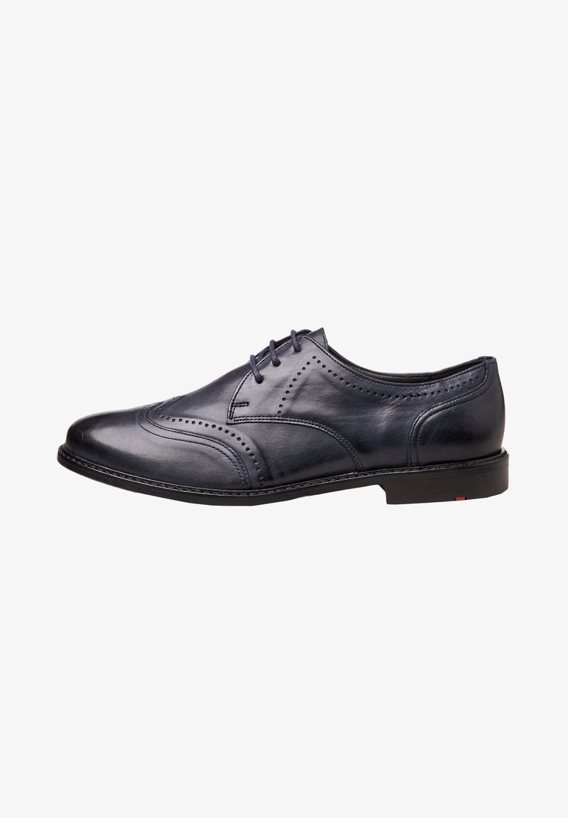 Chaussure habillée pour homme en cuir noir avec détails brogue, fermeture à lacets et talon bas, vue de côté sur fond blanc.