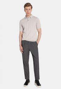 Jasnoszary, prążkowany polo z krótkim rękawem, zestawiony z ciemnoszarymi spodniami i czarnymi trampkami. Prosty design, gładka tekstura, dopasowany krój.