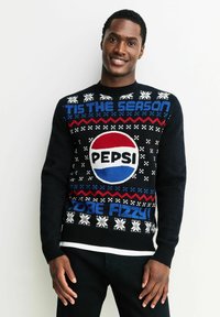 Schwarzer Strickpullover mit einem großen roten, weißen und blauen Pepsi-Logo, festlichen Texten und Schneeflockenmuster in Weiß und Rot.