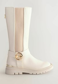 Kniehoge laarzen met een witte leren buitenkant, een beige elastische inzet, een gouden gespsluiting en een gestructureerde zool voor grip.