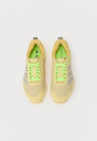 Scarpe da ginnastica gialle con lacci verdi e strisce grigie, dotate di una parte superiore in rete testurizzata e di una suola ammortizzata.