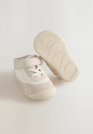 Bezsínű kisgyermek cipők velúrból és szövetből készült felsőrésszel, elasztikus fűzőkkel és tépőzárral. Gumi talp, amely texturált tapadási mintával rendelkezik.