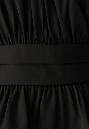 Černé šaty s nařasenou tkaninou se strukturovaným povrchem. Pas je hladký, což kontrastuje s plisovanou sukní.