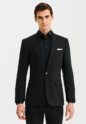 Czarny żakiet o gładkiej teksturze, z pojedynczym zapięciem na guzik i klapami z wycięciem. Posiada dwie przednie kieszenie oraz biały akcent w postaci chusteczki w kieszeni.