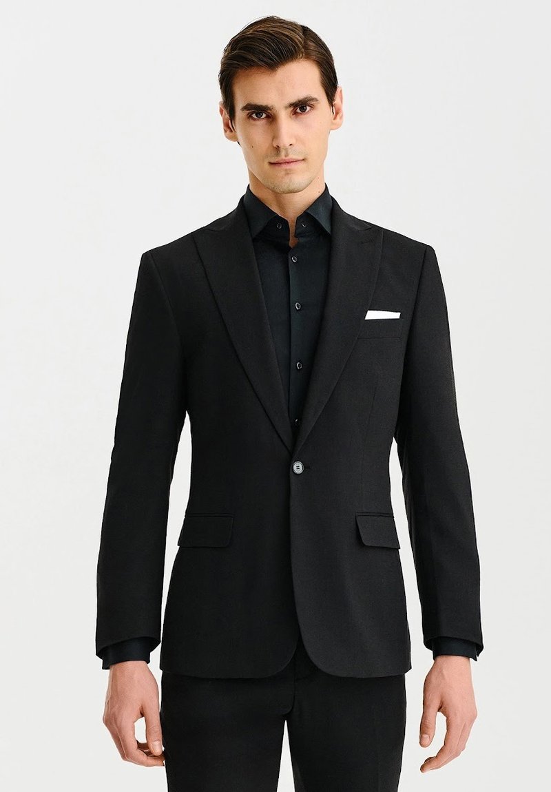 Czarny żakiet o gładkiej teksturze, z pojedynczym zapięciem na guzik i klapami z wycięciem. Posiada dwie przednie kieszenie oraz biały akcent w postaci chusteczki w kieszeni.