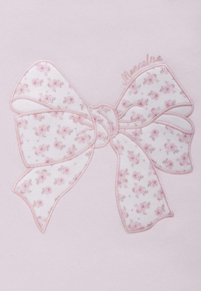 Jasnoróżowy materiał z dużym wzorem w kokardę i białym motywem kwiatowym. Wykończony różowym przeszyciem, opatrzony etykietą "Monnalisa" na górze.