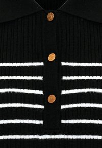 Černý žebrovaný polo top se zvislými bílými pruhy, klasickým límečkem a třemi zlatými knoflíky podél zapínání.