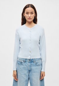 Ανοιχτό μπλε ζακέτα με ριμπ κάτω μέρος και μανσέτες, διαθέτει κούμπωμα μπροστά με κουμπιά και στρογγυλή λαιμόκοψη. Μαλακή υφή, μακριά μανίκια.