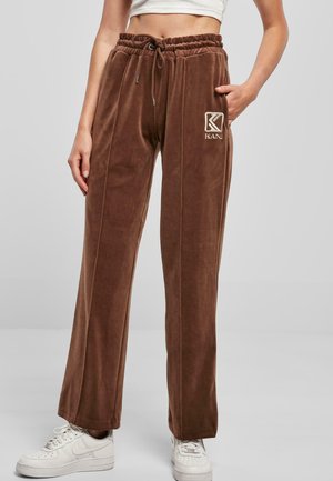 Brown velvet track pants with a drawstring waist, side pockets, and a logo accent. Straight leg design with subtle stitching details.