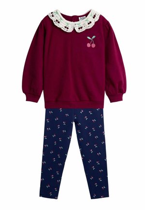 Bordeauxfarbener Pullover mit Spitzenkragen und Kirschen-Stickerei, kombiniert mit dunkelblauen Leggings, die ein Kirschmuster aufweisen.