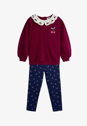 Bordo dukserica s čipkastim ovratnikom i vezenim višnjama, u kombinaciji s tamnoplavim tajicama s uzorkom višnje.