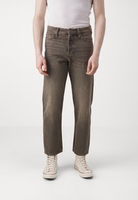 Brune denim jeans med rett snitt, falmet tekstur og fem-lommersdesign, paret med lyse høye sneakers.